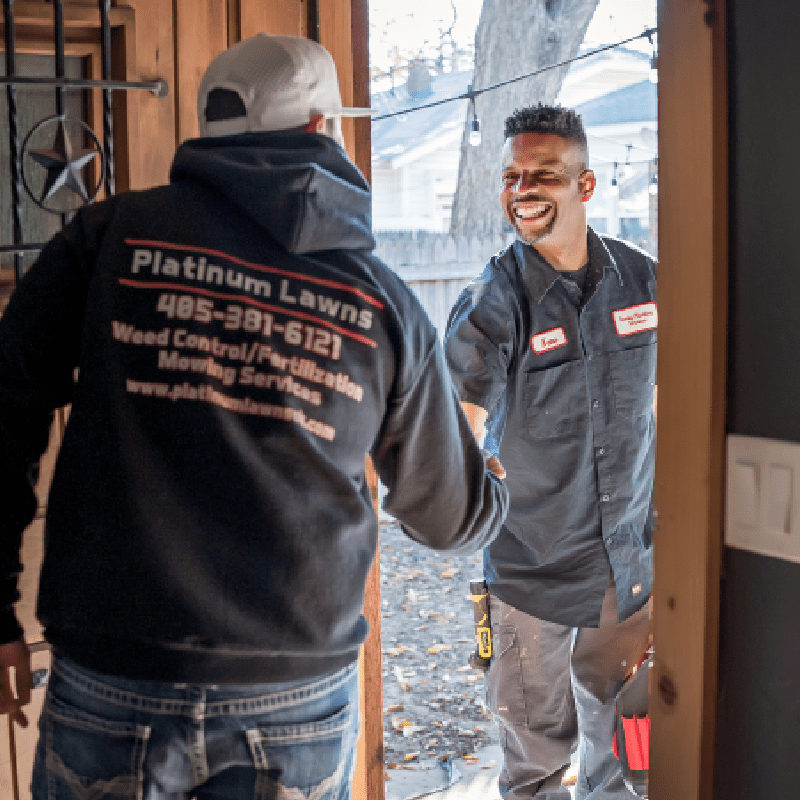 Two workers in uniform shaking hands at a doorstep